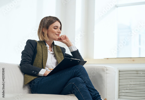 Business woman in suit with documents sitting on sofa indoors