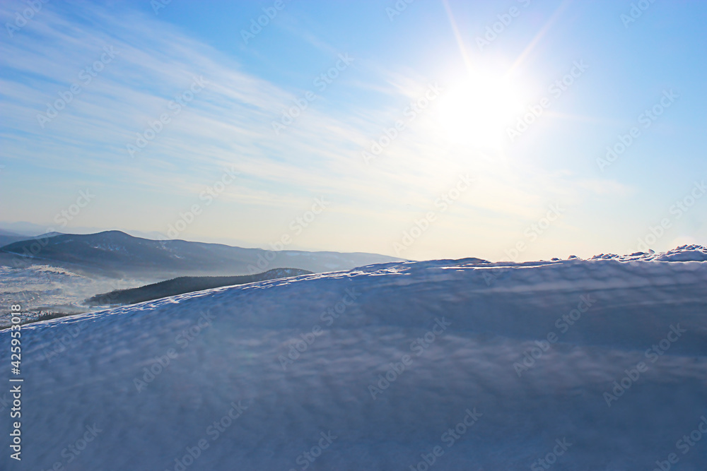 Winter landscape. Snowdrift against the background of mountains and blue sky and shining sun