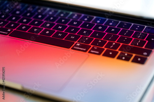 Close up of laptop partially open with colorful prism light and keyboard