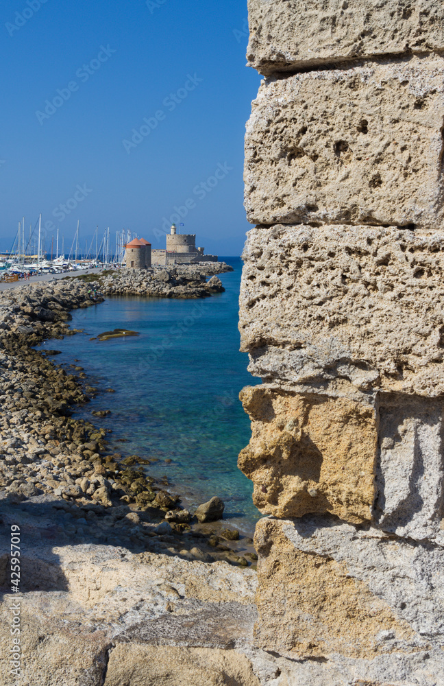 Picturesque view from the fortress wall of the pier with windmills and medieval fort (Rhodes, Greece)