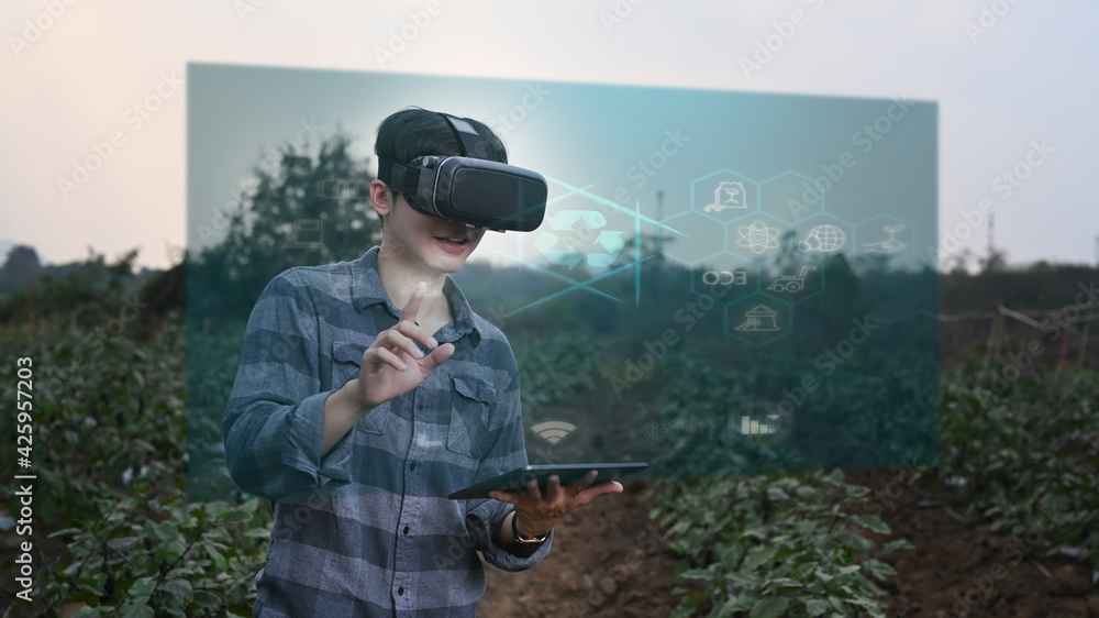 Fototapeta premium Futuristic farmer holding digital tablet and wearing visual reality glasses technology with futuristic augmented reality holograms for development agricultural products. Agriculture technology concept