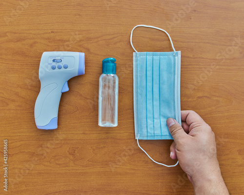 Equipo para protegerse contra COVID con un termómetro, gel antibacteriana, aerosol y mascarilla cubrebocas, todo para prevenir photo