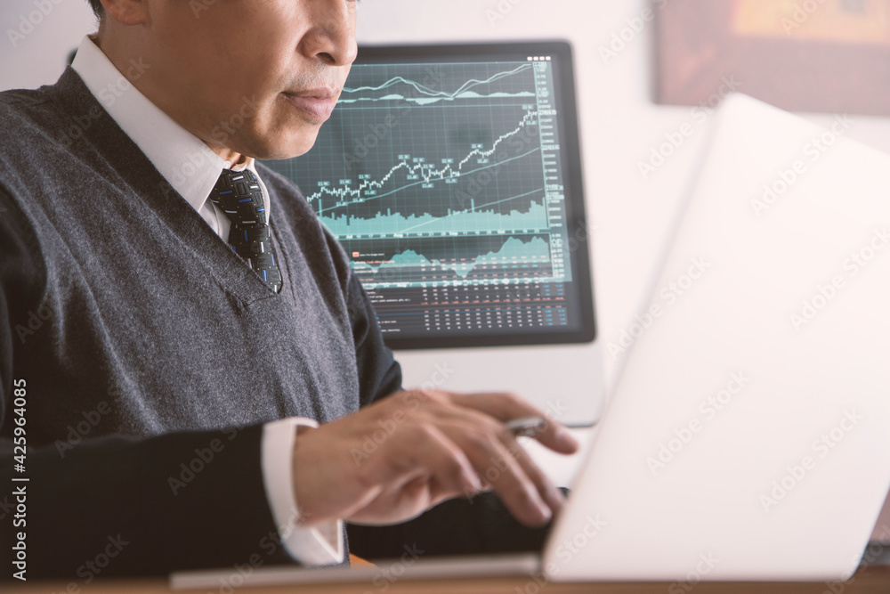 Asian businessmen in a modern office using a modern laptop comupter reviewing stock exchange market and business performance and investment risk analysis or return on investment, ROI. Asian businessmen in a modern office using a modern laptop comupter reviewing stock exchange market and business performance and investment risk analysis or return on investment, ROI.