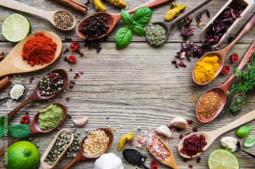 A selection of various colorful spices on a wooden table in spoons