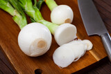 Cut green young onion bulbs on wooden desk during cooking, nobody