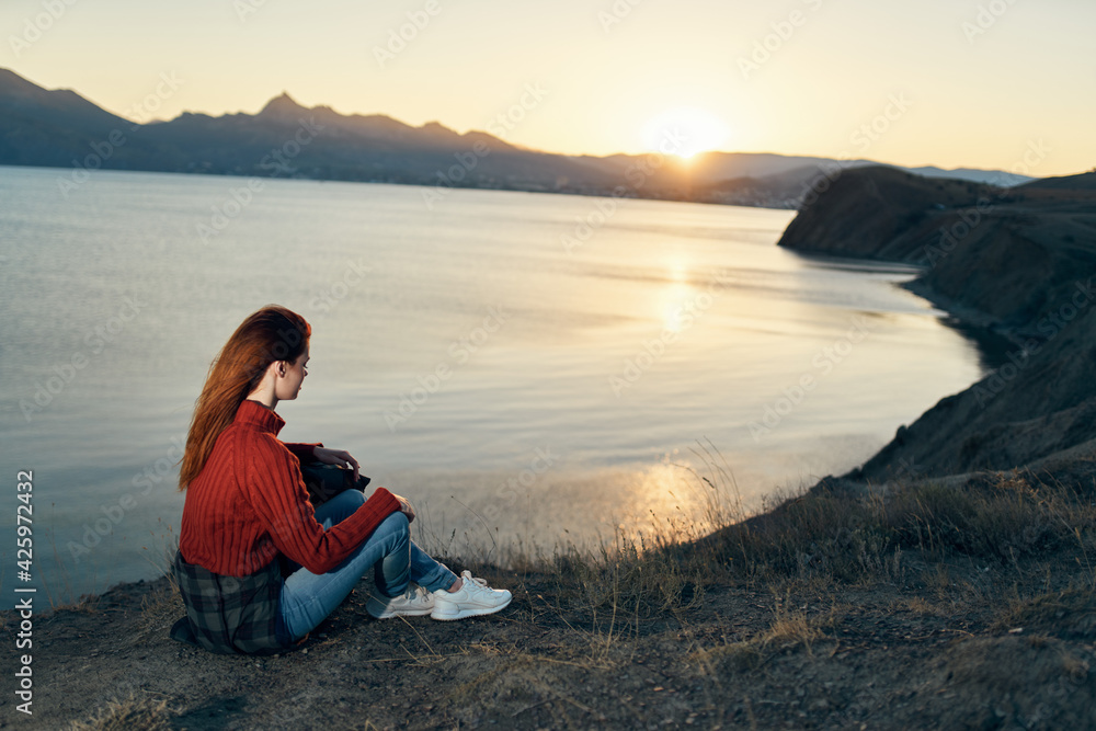 woman sits on the ground in nature in the mountains near the sea adventure sunset