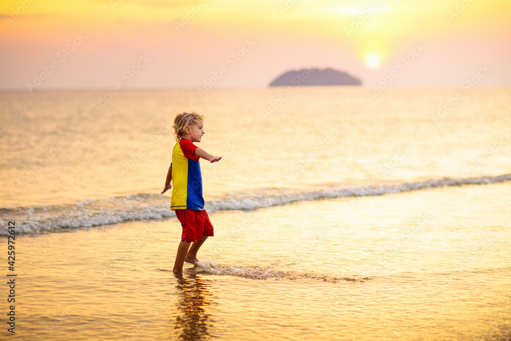Child playing on ocean beach. Kid at sunset sea. Child playing on ocean beach. Kid at sunset sea.