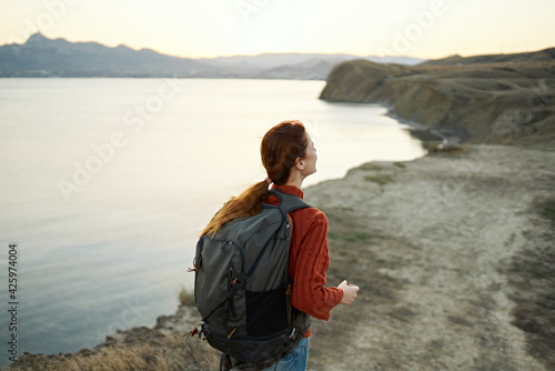 woman tourist with a backpack in the mountains in nature walks along the road and a car in the distance