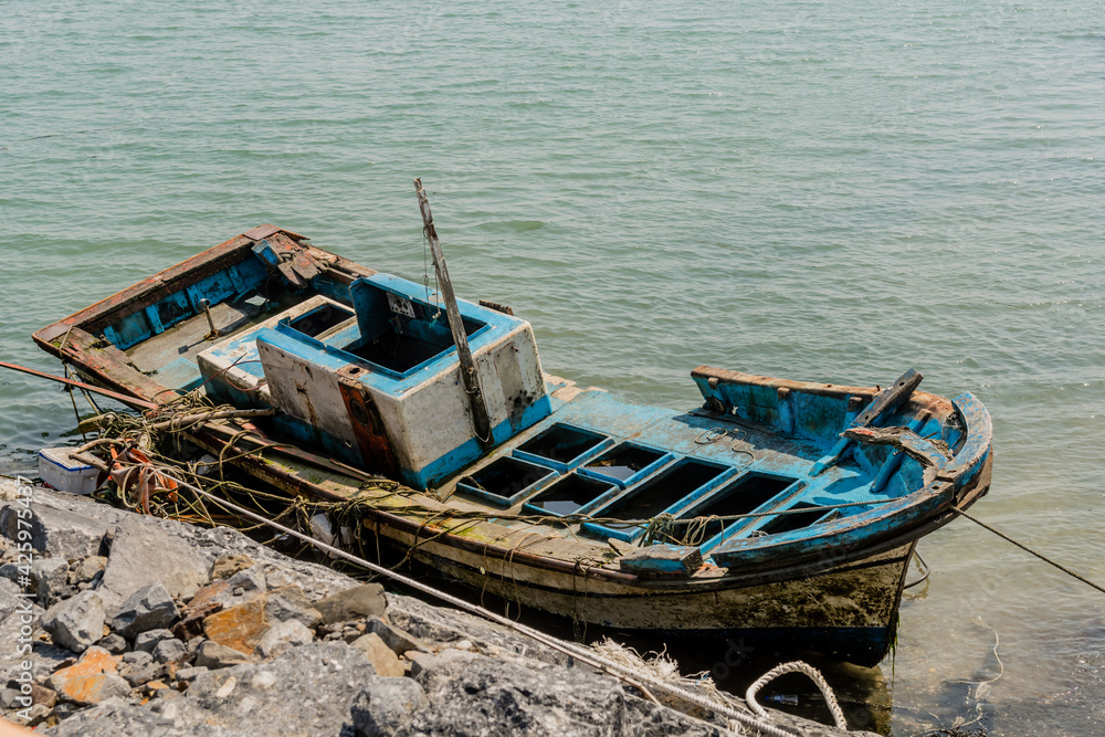Damage fishing boat moored to rock pier