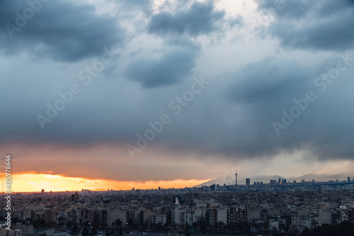Tehran-Iran skyline at a moody sunset after a heavy storm. with Milad tower and beautiful snow covered mountains and amazing clouds in the background.
