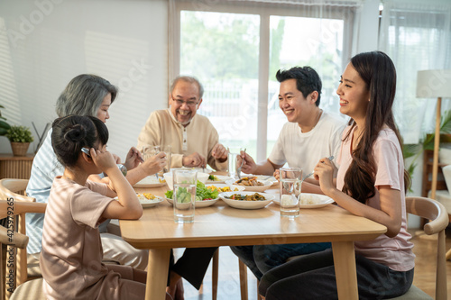 Asian big family enjoy eating food together  sitting on dining table.