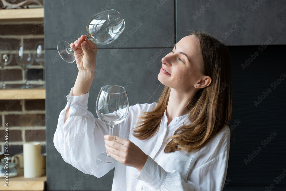 Woman takes a glass out of the dishwasher while standing in the kitchen Woman takes a glass out of the dishwasher while standing in the kitchen