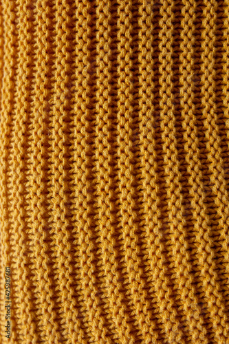 Knitted sweater fabric close up, material texture, yellow warm sweater macro