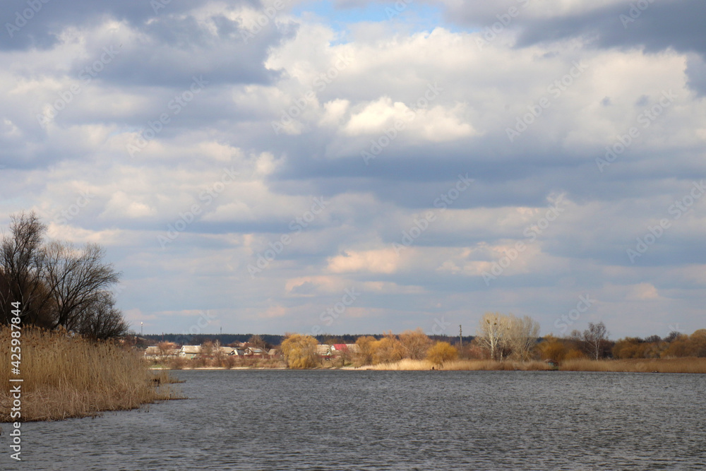 Panoramic view of the river. Spring landscape with river and cloudy sky. Stormy windy weather