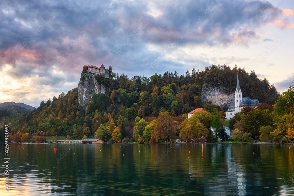 Scenic view of the Bled castle on the cliff at sunset, Bled lake (Blejsko jezero) in Slovenia, amazing autumn landscape with colored sky. Outdoor travel background
