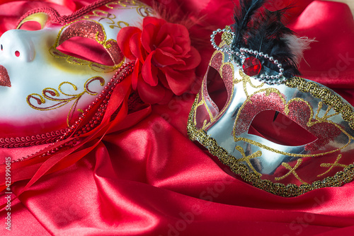 Venetian masks decorated by crystal and flowers on red silk background close up