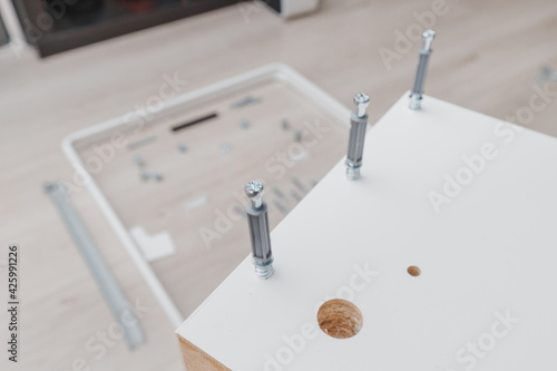 Group of confirmatory screeds and white chipboard, as a concept of fasteners and work on the assembly of furniture at home photo