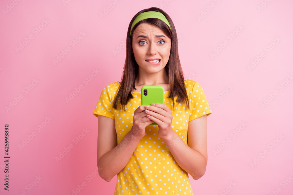 Obraz premium Photo of young attractive uncertain unsure doubtful girl bite lips hold cellphone isolated on pink color background