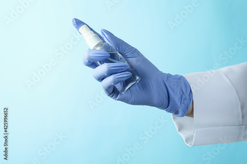 Doctor in medical gloves hold antiseptik on blue background photo