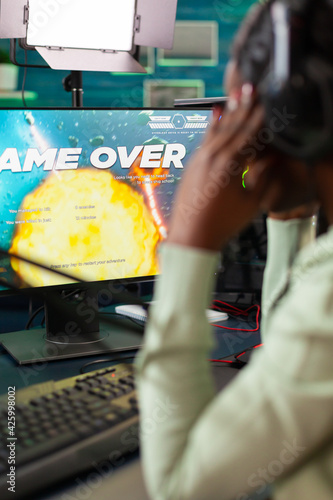 Afro esport player suffering lose defeat during space shooter live tournament. Professional gamer streaming online video games with new graphics on powerful computer.
