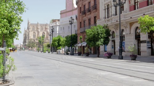 Time-lapse of streets of Seville.  Constitution Avenue, Seville Cathedral in background. People walking, tram passing from boughs sides. Sunny summer day 