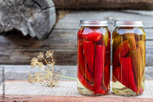 Chili peppers in a glass jar on a wooden table, homemade pickles