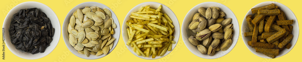Snacks on a yellow background. View from above. Pistachios, pumpkin seeds, sunflower seeds, crackers, fried potatoes Snacks on a yellow background. View from above. Pistachios, pumpkin seeds, sunflower seeds, crackers, fried potatoes