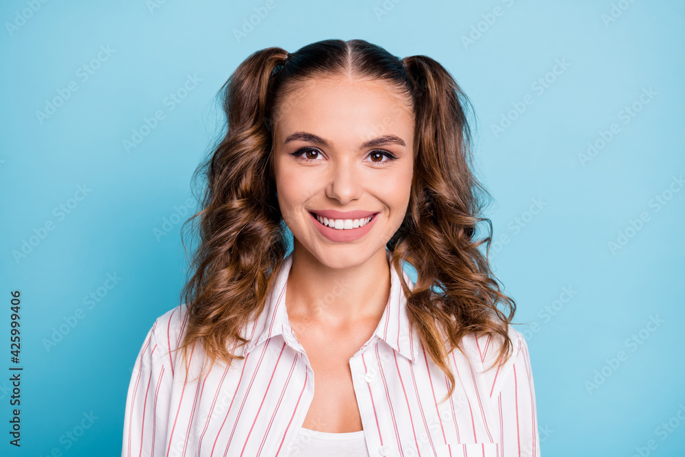 Photo portrait of happy girl with ponytails smiling in striped shirt isolated on bright blue color background Photo portrait of happy girl with ponytails smiling in striped shirt isolated on bright blue color background