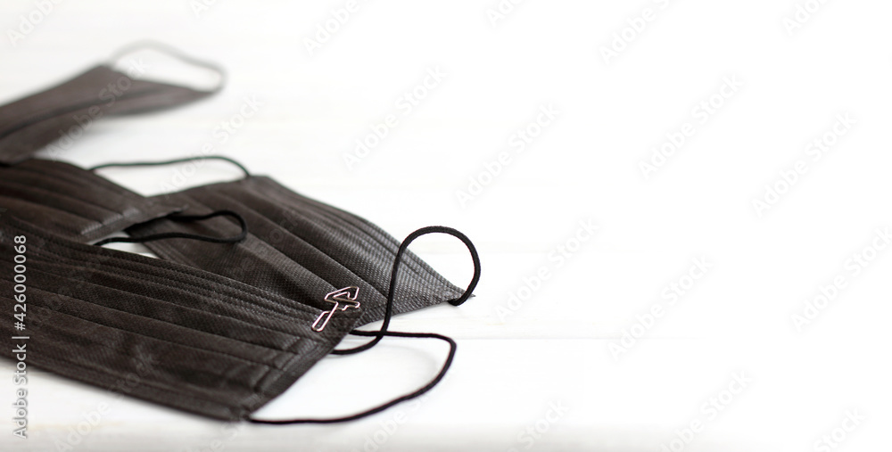 one of the black medical masks lying on a light background is numbered. fourth wave one of the black medical masks lying on a light background is numbered. fourth wave