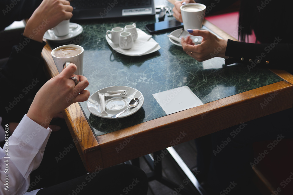 meeting in a cafe for a cup of coffee. laptop on the table. Conversation and discussion. Business and work concept. Without the visibility of faces