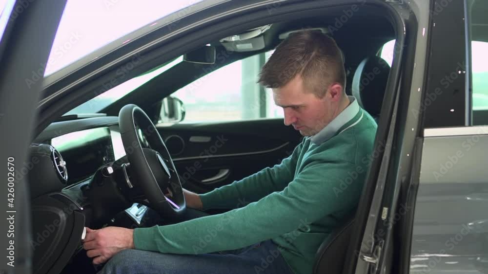 Male buyer sitting inside new car and testing before buying or renting at dealership spbas. Male buyer sitting inside new car and testing before buying or renting at dealership spbas.