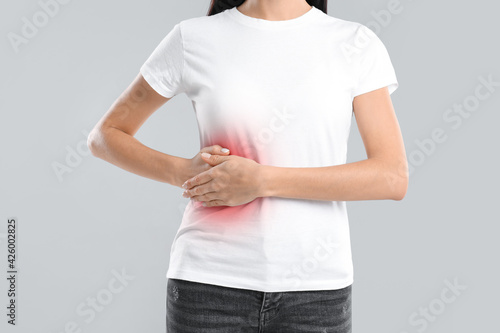 Woman suffering from liver pain on grey background, closeup