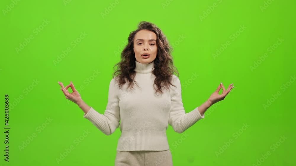 The woman is standing and looking at the camera. She is doing breathing exercises and meditation. She is smiling. She is standing on a green background. Green screen. 4K The woman is standing and looking at the camera. She is doing breathing exercises and meditation. She is smiling. She is standing on a green background. Green screen. 4K