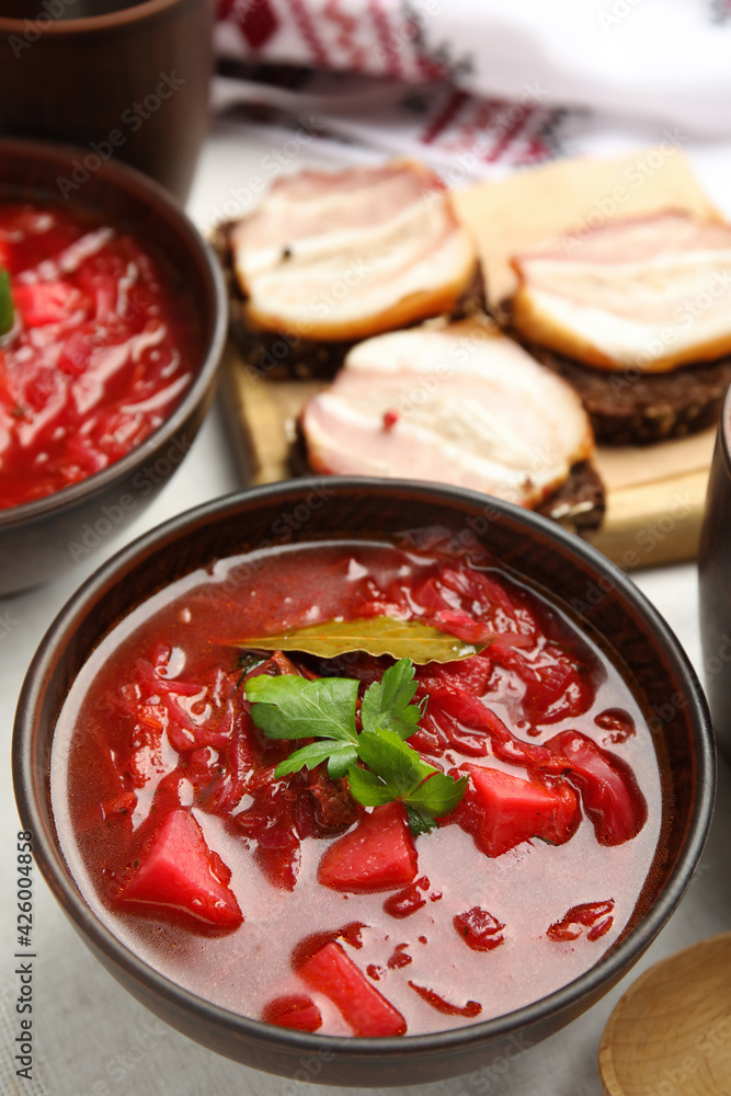 Stylish brown clay bowl with Ukrainian borsch served on white tablecloth Stylish brown clay bowl with Ukrainian borsch served on white tablecloth