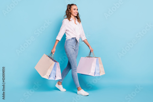 Full length body size photo of girl keeping packages after sale shopping in mall isolated bright blue color background