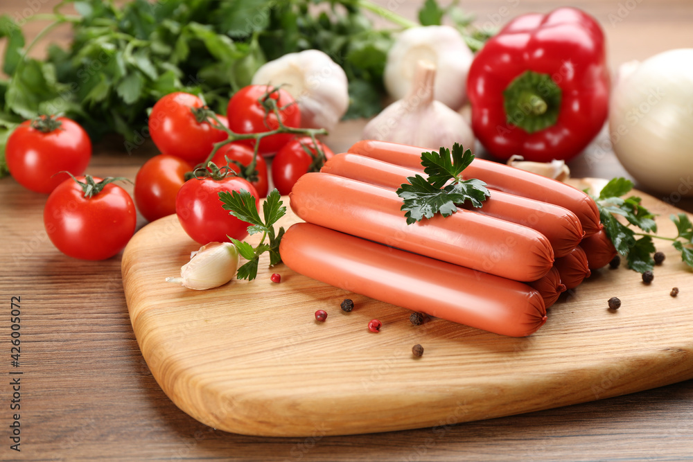 Fresh raw vegetarian sausages with parsley and vegetables on wooden table