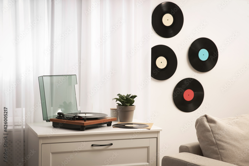 Fototapeta premium Stylish turntable on white chest of drawers and vinyl records indoors