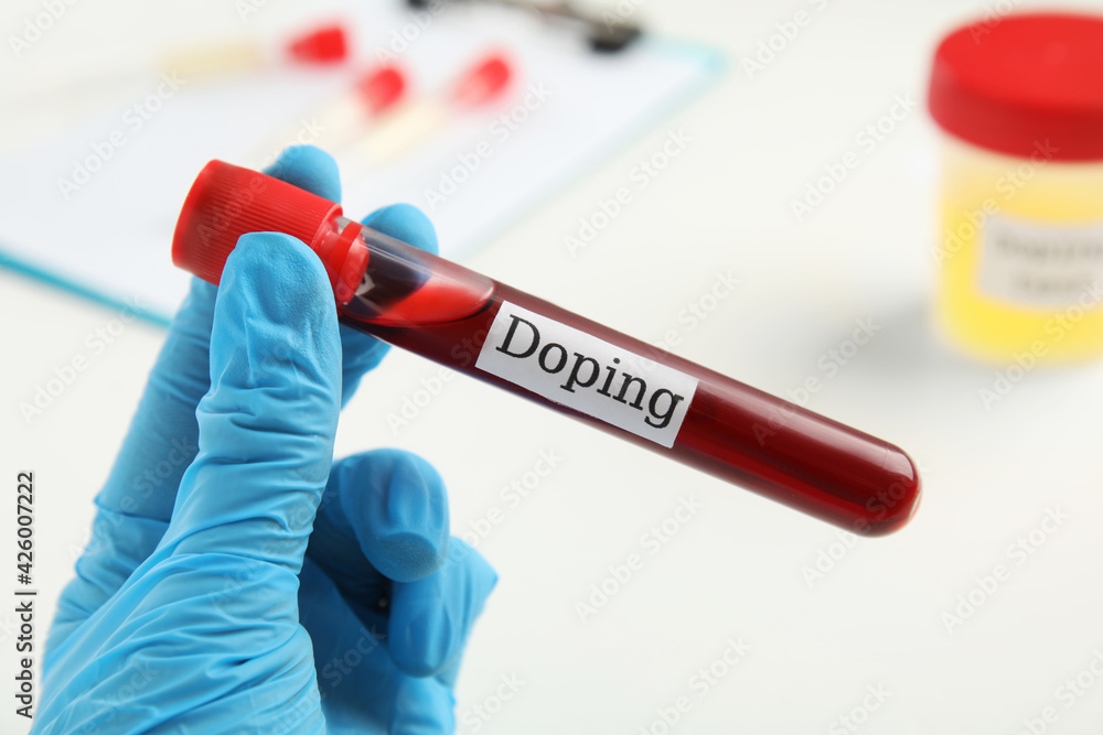 Obraz premium Doctor holding test tube with blood sample over table, closeup. Doping control