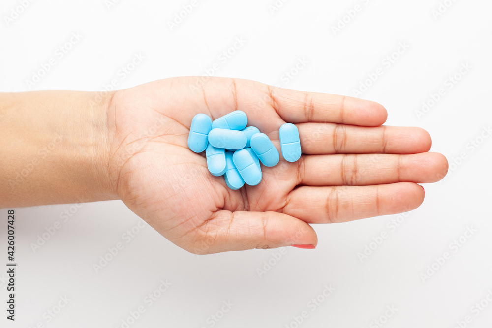 Macro Close up of medicinal or herbal cyan tablet on female hand palm. Top view, white background. Macro Close up of medicinal or herbal cyan tablet on female hand palm. Top view, white background.