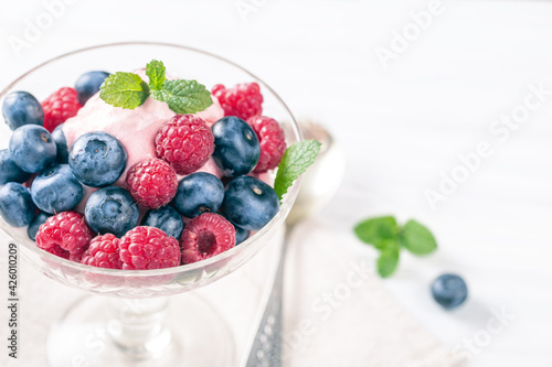 Blueberry raspberry dessert with mint in ice-cream bowl, low shallow focus with copy space