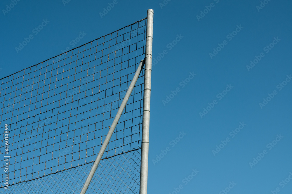 a high wire mesh fence at blue sky