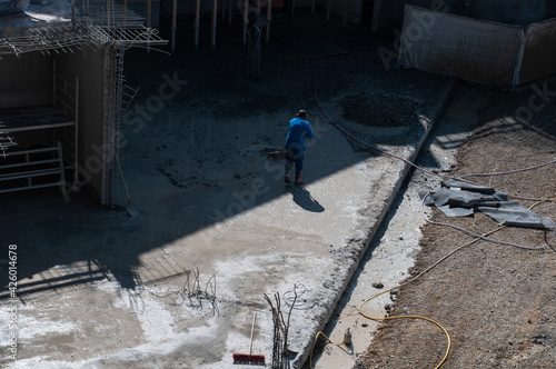 an unrecognizable person cleaning the floor at a construction site