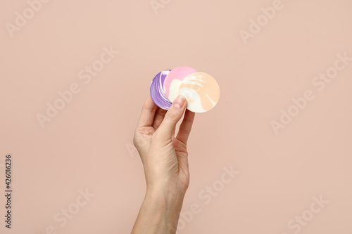 Colorful Cosmetic Sponges in the hand for make-up against the neautral beige wall background, trendy earth tones, concept of work make up artist, salon service, banner, coupon, copy space photo