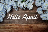 Hello April text and spring flower decoration on wooden background