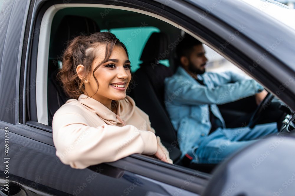 Careful driving. Beautiful young indian couple sitting on the front passenger seats and smiling while handsome man driving a car