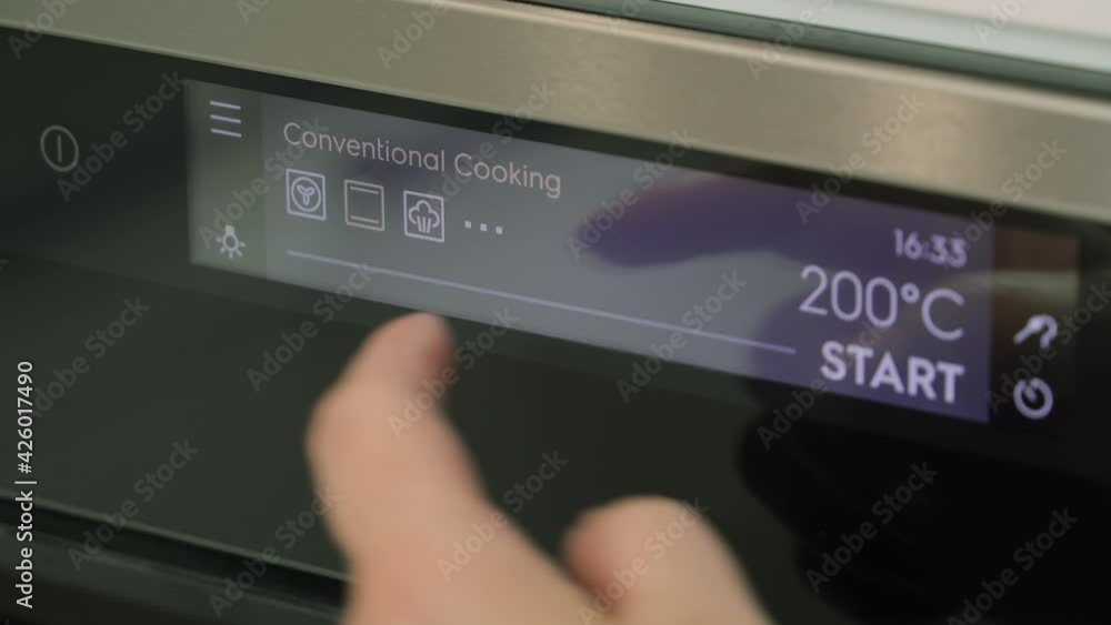 Touch panel of a modern electric oven. Temperature readings on display of a modern oven. Turning on the oven before cooking. Woman turn temperature on oven panel. Heating oven to cooking temperature. Touch panel of a modern electric oven. Temperature readings on display of a modern oven. Turning on the oven before cooking. Woman turn temperature on oven panel. Heating oven to cooking temperature.