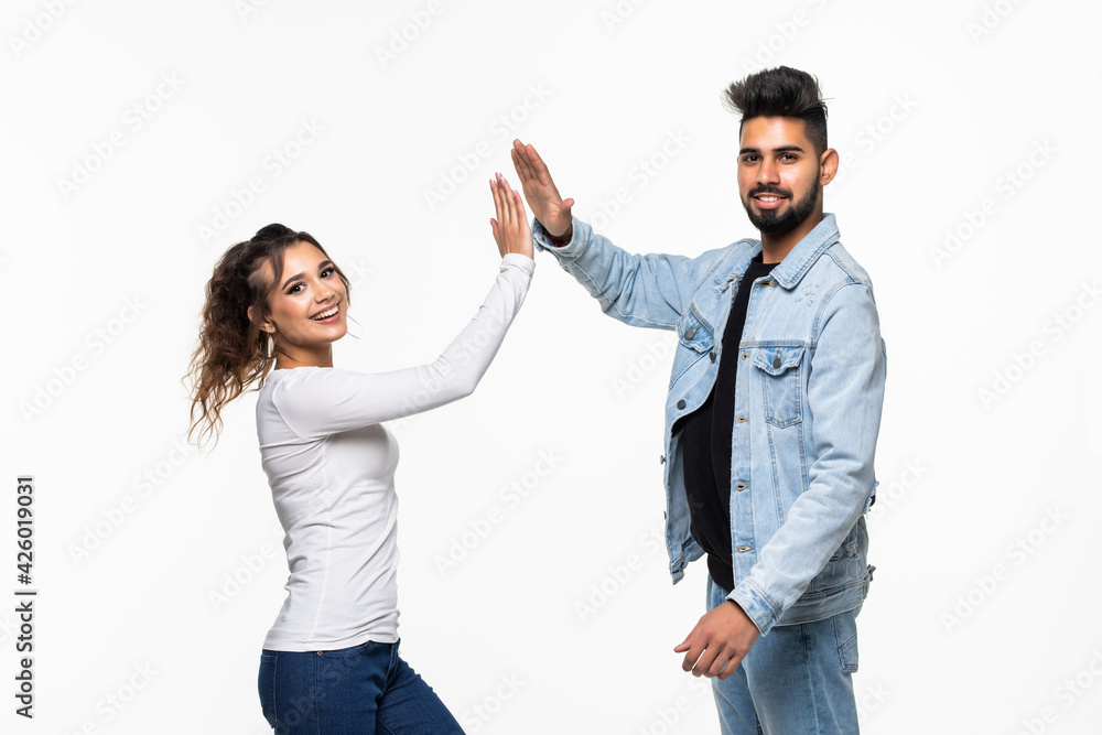 Portrait of an indian young couple giving high five over gray background Portrait of an indian young couple giving high five over gray background