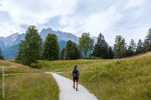 Back view of Traveler, Backpacker walking and enjoy nature. Mountain range wetterstein mountains, Waxenstein and Zugspitze peaks. Wetterstein range Northern Limestone Alps Bayern Germany Europe