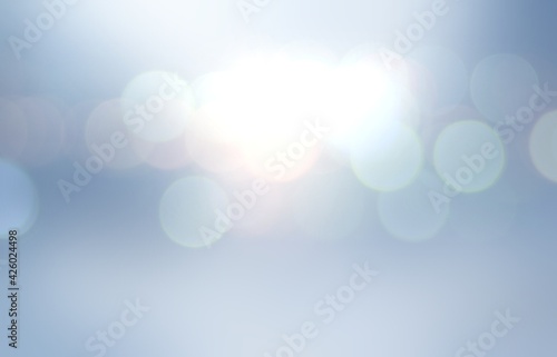 Bokeh flares on cool light blue backgrond for winter holidays decor.