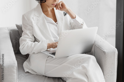 Cropped portrait of businesswoman working with laptop while siting in chair in office.